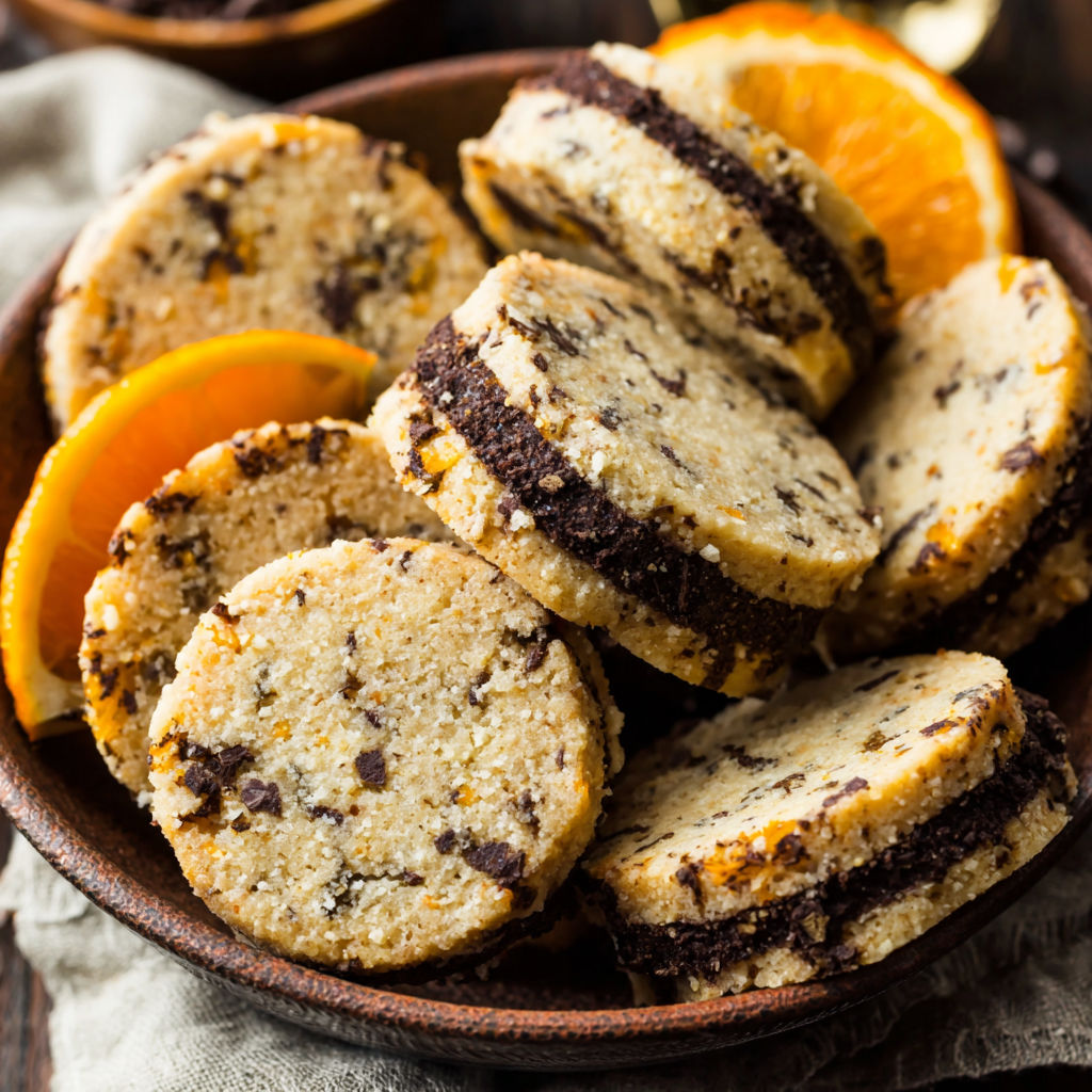 A bowl of cookies with orange slices on top.
