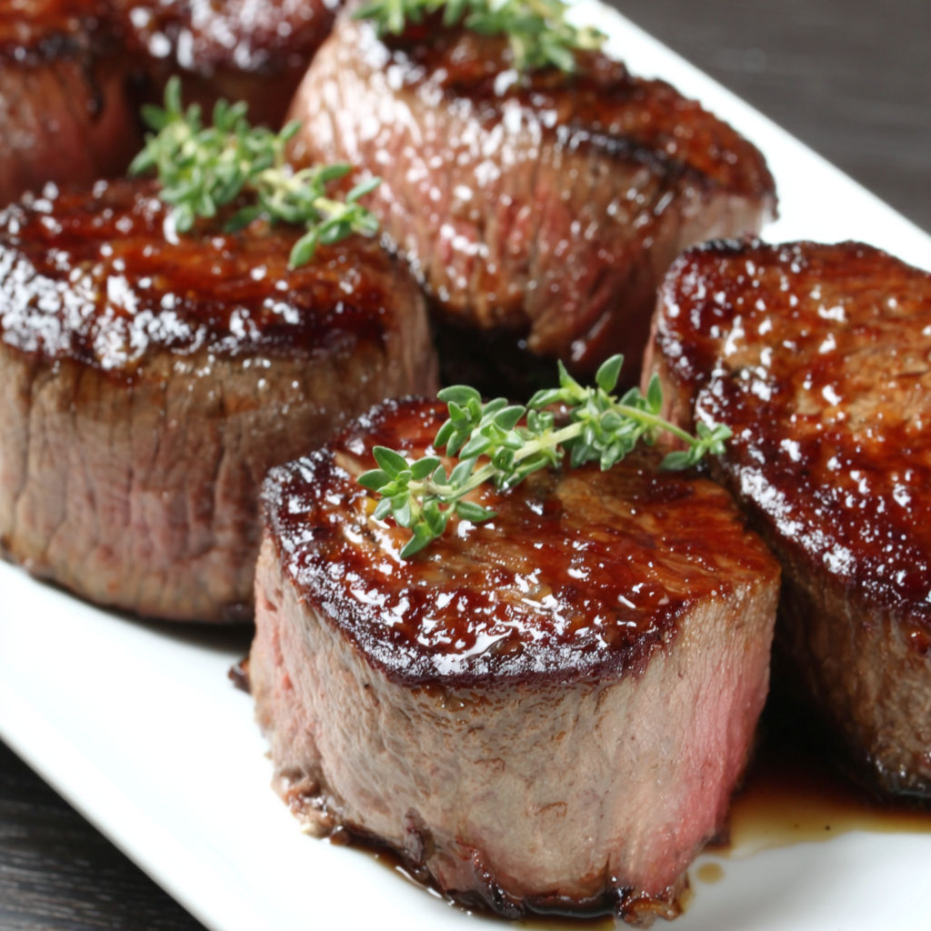 A plate of meat with herbs on top.