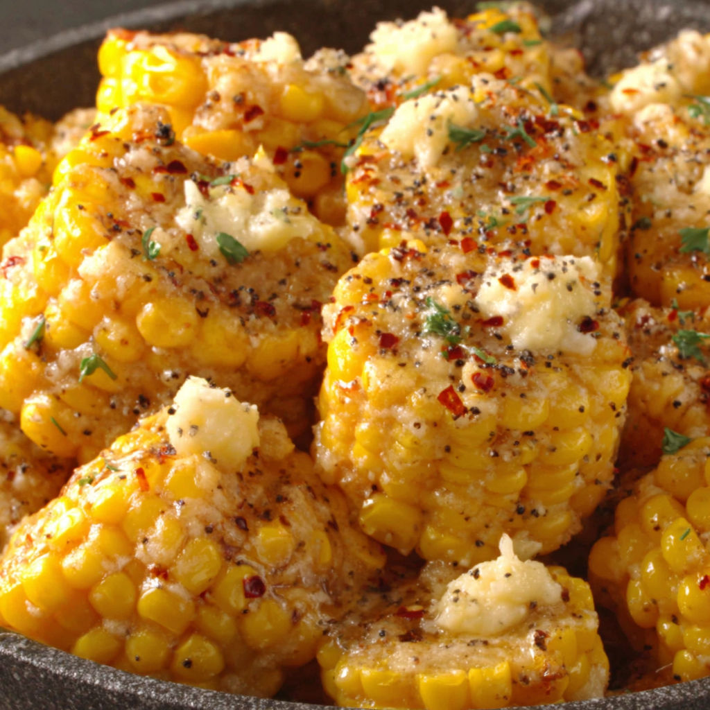 A bowl of corn with cheese and spices.