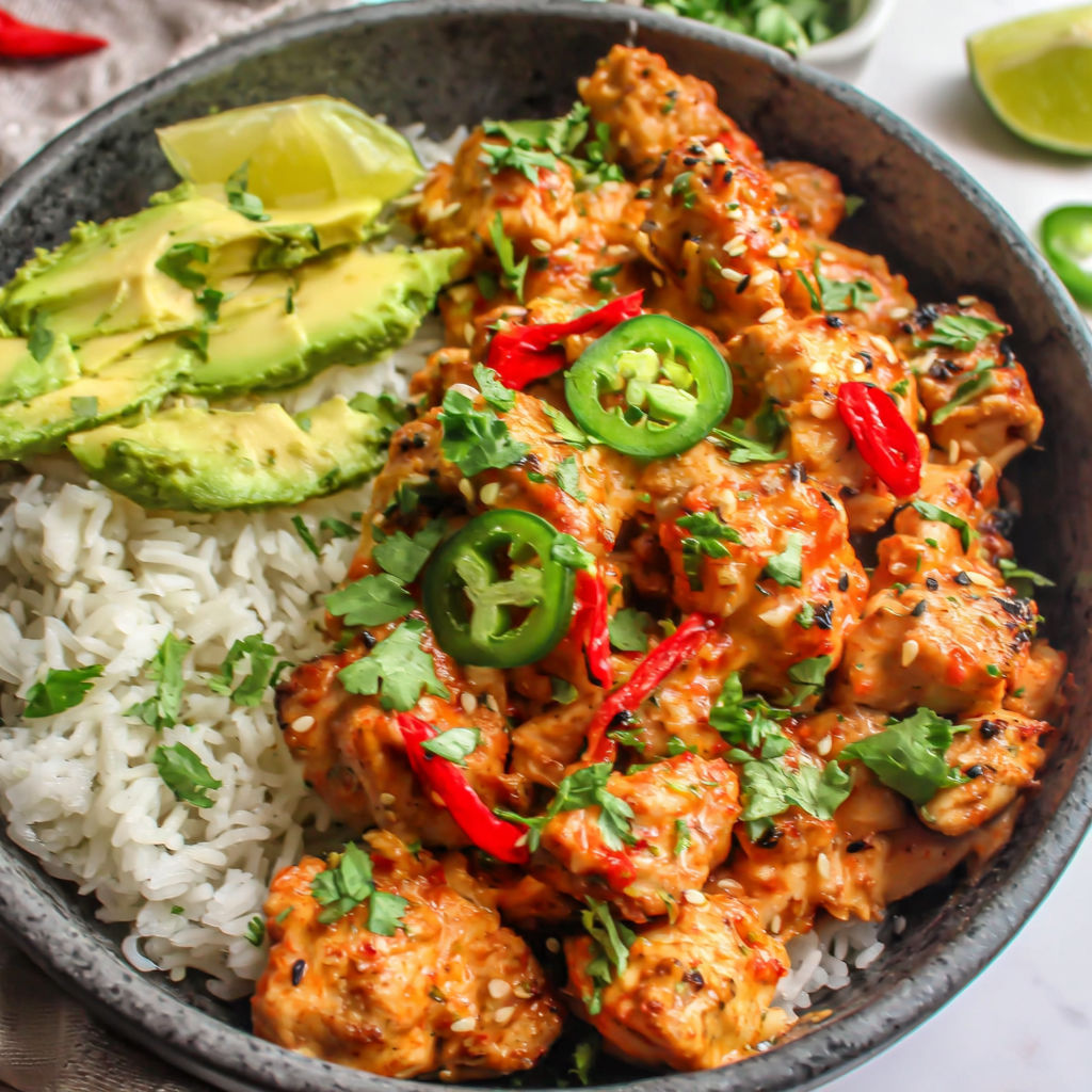 A bowl of food with rice, chicken, peppers, and lime.