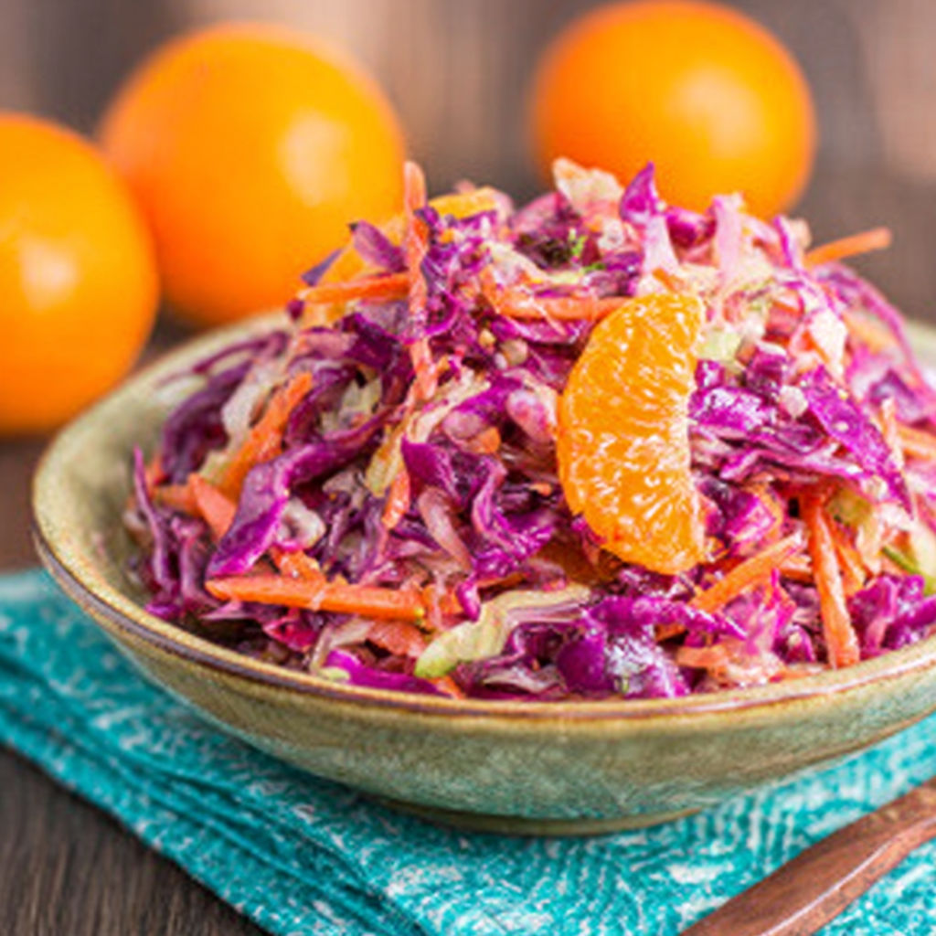 A bowl of coleslaw with orange slices on top.