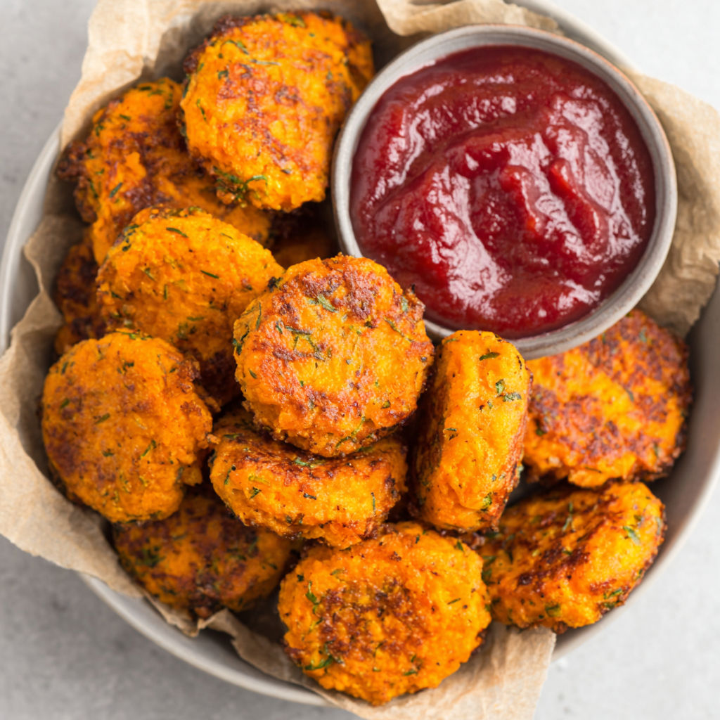 A bowl of food with a ketchup dipping sauce.