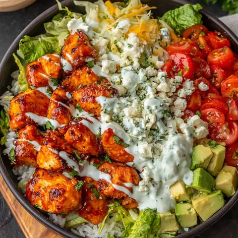 A bowl of food with chicken, rice, tomatoes, and cheese.