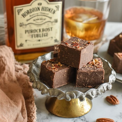 A bottle of bourbon whiskey sits next to a plate of chocolate squares.