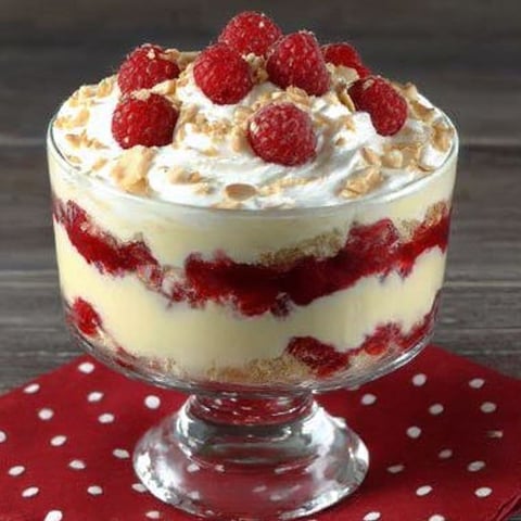 A dessert in a glass dish with a red polka dot tablecloth.
