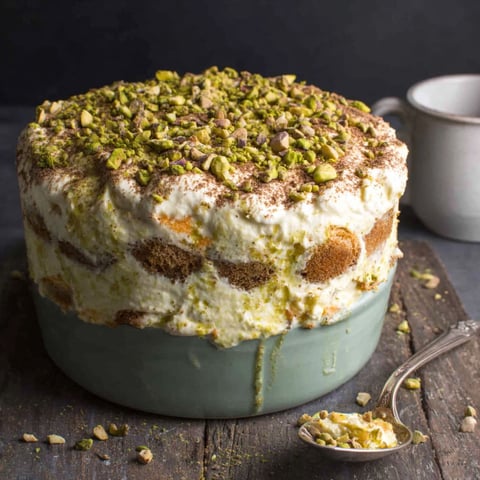 A cake with pistachio nuts and almonds on top.