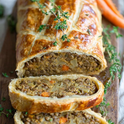A pastry with meat and vegetables on a wooden board.