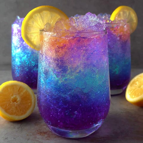 A glass of purple drink with lemon slices in it.