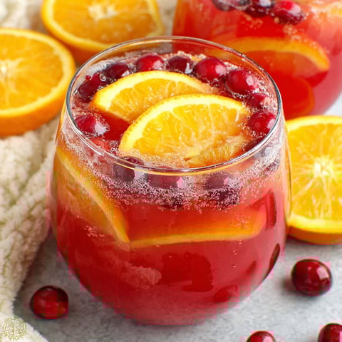 A glass of red wine with orange slices in it.