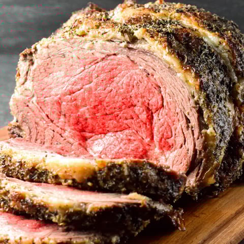 A large cut of meat on a wooden board.