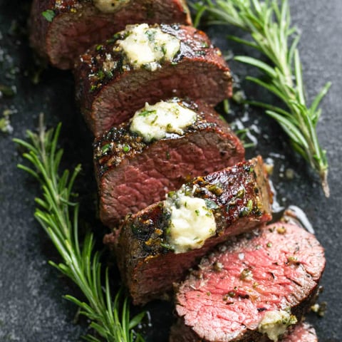 A close up of a steak with cheese on top.