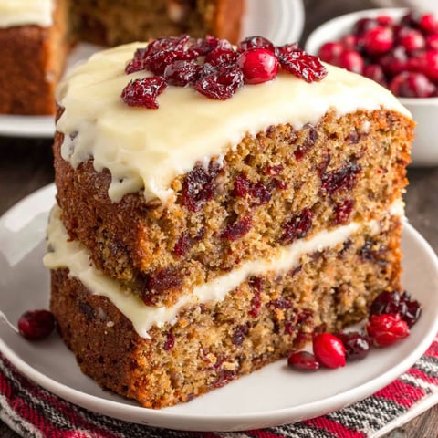 A slice of cake with white frosting and red berries on top.