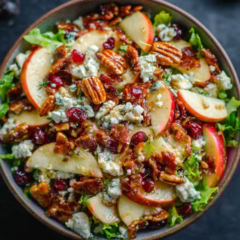 A bowl of salad with apples, nuts, and blue cheese.
