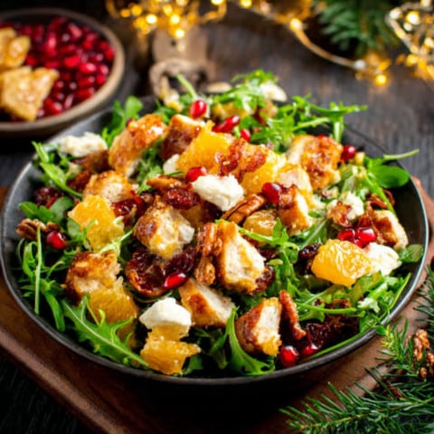 A bowl of salad with oranges and cheese.