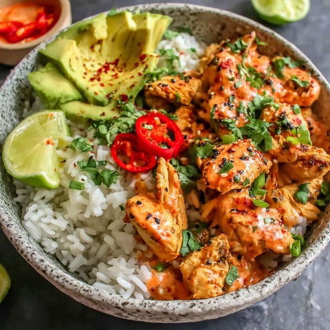 A bowl of rice and meat with a red sauce.