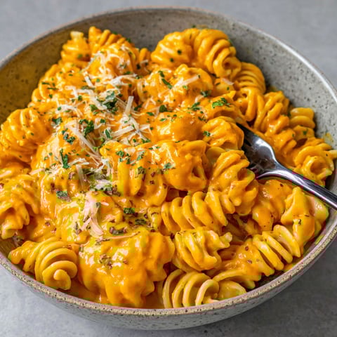 A bowl of pasta with cheese and sauce.