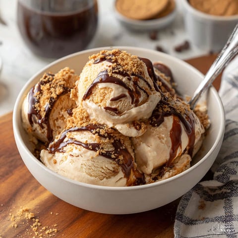 A bowl of ice cream with chocolate sauce and crumbles.