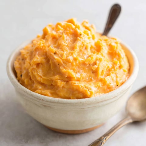 A bowl of mashed potatoes with a spoon in it.