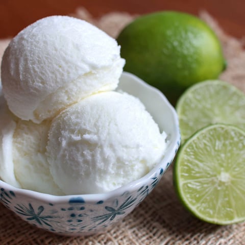 A bowl of ice cream with limes on the side.