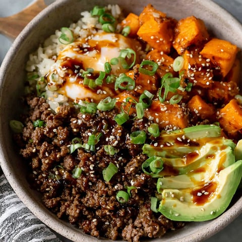 A bowl of food with rice, eggs, and vegetables.