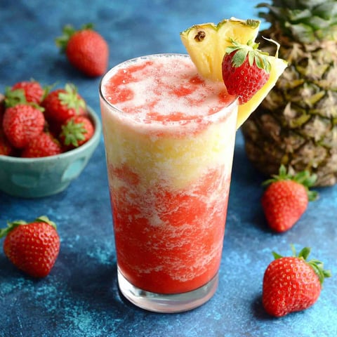 A glass of pink and yellow drink with a strawberry on top.