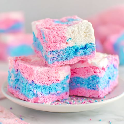 A stack of three colorful dessert squares on a plate.