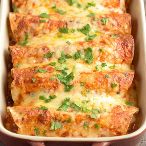 A dish of lasagna with cheese and green herbs.