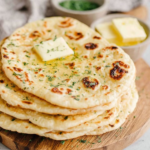 A stack of tortillas with butter on top.