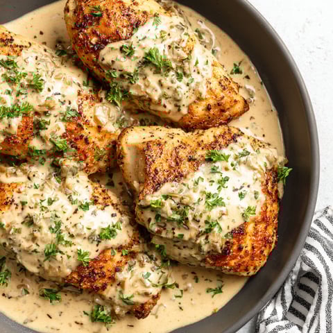 A bowl of chicken covered in a creamy sauce.